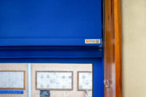 Blue roller blind in a wooden window frame with P-clip fitted
